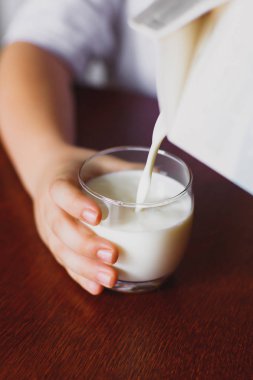 Taze, ev yapımı, mağaza süt bir kupa dökülür. Çocuk bir kupa tutuyor. Süt jet. Portre