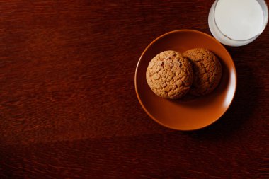 Bir bardak taze ev yapımı süt ve lezzetli yulaf ezmeli kurabiye ahşap bir masa üzerinde. Anne sağlıklı bir kahvaltı yaptım. Üstten görünüm. Metin yer