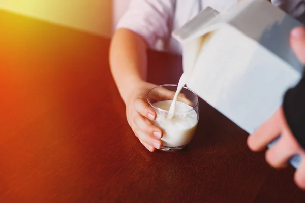 Fresh, homemade, store milk is poured into a mug. The boy is holding a mug. The jet of milk. Closeup