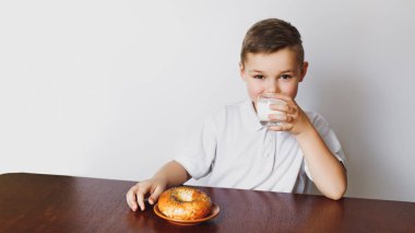 Genç çocuk beklemekten yorgun. Sabah, sağlıklı kahvaltı, ev yapımı süt ve lezzetli bir simit. Çocuk yorgun.