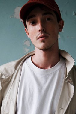 Bir kırmızı beysbol şapkası ve yağmurluk genç bir adam portresi. Moda portre modeli. Beyaz gömlekli bir adam.