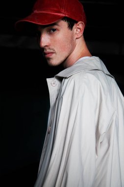 Bir kırmızı beysbol şapkası ve yağmurluk genç bir adam portresi. Moda portre modeli. Beyaz gömlekli bir adam.