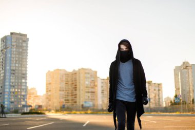 Şehrin sprey ile genç adam el boyama için yürüyüş yapabilirsiniz. Gün batımında maskesinde kukuletalı Vandalist geliyor.