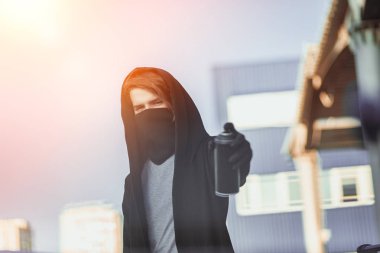 Adam maske ve eldiven bir sprey boya ile olabilir tutuyor. Sokak vandalizm, kentsel tarzı. Grafiti çizimler. Aerosol elinde.