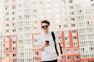 Genç adam gider ve onun elinde telefon ile gülüyor. Bina arka plan üzerinde