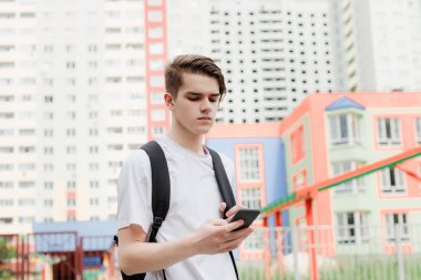 Öğrenci telefonunu kullanma. Beyaz gömlek ve siyah sırt çantası. Sokak stili