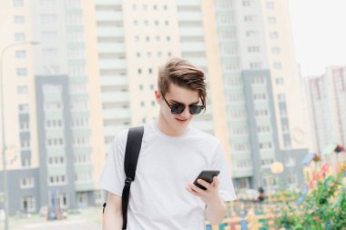 Güneş gözlüklü genç adam telefonu ile mesaj yazın