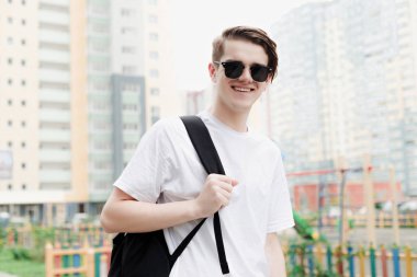 Güneş gözlüğü ve siyah sırt çantası ile gülen adam. Sokak stili