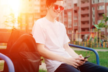 Kırmızı gözlük ile telefon ve gülümseyen genç adam oturma portre