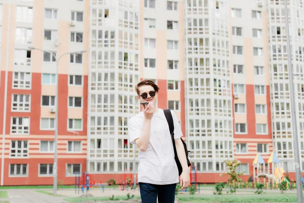 Öğrenci gider ve onun elinde telefonla konuşuyor. Sokak tarzı. Açık