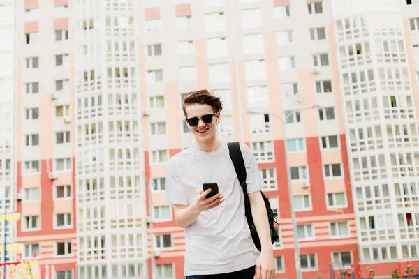 Genç adam gider ve onun elinde telefon ile gülüyor. Bina arka plan üzerinde