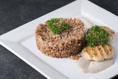 Buğday lapası beyaz tabakta diyet etli şefkatle sunulmaktadır.