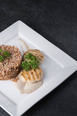 Buğday lapası beyaz tabakta diyet etli şefkatle sunulmaktadır.