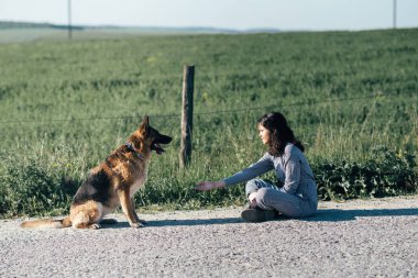 Sevimli kız köpeğini alanın arka planı ile oynarken.