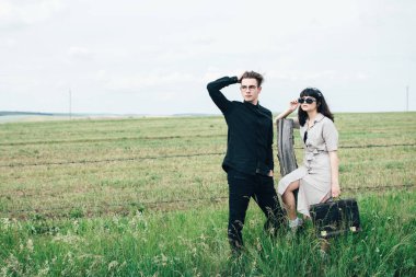 Sevimli genç adam bir şehir arkasında yeşil bir arka plan üzerinde güzel bir kızın yanında ayakta.