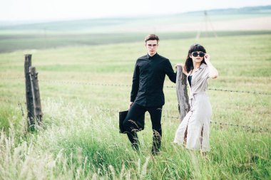 Sevimli genç adam bir şehir arkasında yeşil bir arka plan üzerinde güzel bir kızın yanında ayakta.