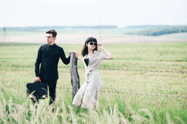 Sevimli genç adam bir şehir arkasında yeşil bir arka plan üzerinde güzel bir kızın yanında ayakta.