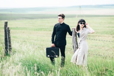 Sevimli genç adam bir şehir arkasında yeşil bir arka plan üzerinde güzel bir kızın yanında ayakta.