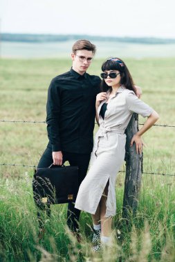 Sevimli genç adam bir şehir arkasında yeşil bir arka plan üzerinde güzel bir kızın yanında ayakta.