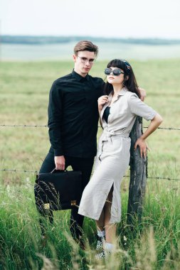 Sevimli genç adam bir şehir arkasında yeşil bir arka plan üzerinde güzel bir kızın yanında ayakta.