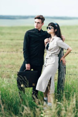 Sevimli genç adam bir şehir arkasında yeşil bir arka plan üzerinde güzel bir kızın yanında ayakta.