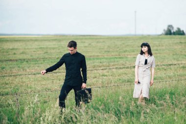 Sevimli genç adam bir şehir arkasında yeşil bir arka plan üzerinde güzel bir kızın yanında ayakta.