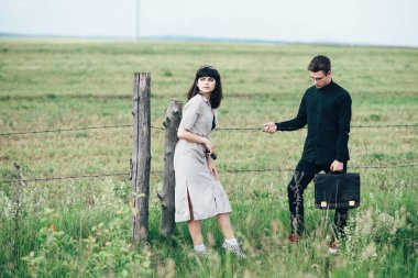 Sevimli genç adam bir şehir arkasında yeşil bir arka plan üzerinde güzel bir kızın yanında ayakta.