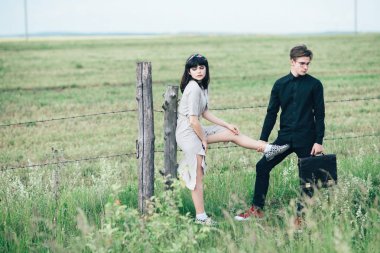 Sevimli genç adam bir şehir arkasında yeşil bir arka plan üzerinde güzel bir kızın yanında ayakta.