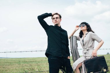 Sevimli genç adam bir şehir arkasında yeşil bir arka plan üzerinde güzel bir kızın yanında ayakta.