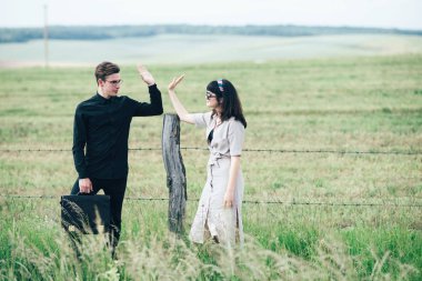 Sevimli genç adam bir şehir arkasında yeşil bir arka plan üzerinde güzel bir kızın yanında ayakta.