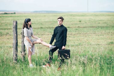 Sevimli genç adam bir şehir arkasında yeşil bir arka plan üzerinde güzel bir kızın yanında ayakta.