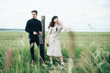 Sevimli genç adam bir şehir arkasında yeşil bir arka plan üzerinde güzel bir kızın yanında ayakta.