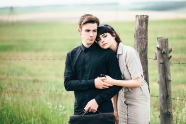 Sevimli genç adam bir şehir arkasında yeşil bir arka plan üzerinde güzel bir kızın yanında ayakta.