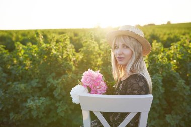 Sevimli Genç sarışın kız onun elinde pions ile yeşil arka plana karşı sandalyeye oturur