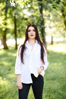 Sevimli genç esmer kız parkta yeşil arka plan güzel profesyonel makyaj ile.