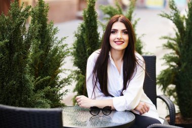 Sevimli genç esmer kız güzel güneşli bir günde bir sokak kafede oturan güzel profesyonel makyaj ile.