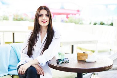 Sevimli genç esmer kız güzel güneşli bir günde bir sokak kafede oturan güzel profesyonel makyaj ile.