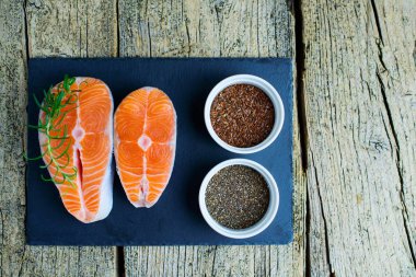 İki somon biftek yalan bir kara tahta üzerinde ve orada yanında vitamin ve chia ve keten tohumu vardır. Üstten görünüm. Vitamin almak için seçim.