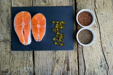 İki somon biftek yalan bir kara tahta üzerinde ve orada yanında vitamin ve chia ve keten tohumu vardır. Üstten görünüm. Vitamin almak için seçim.