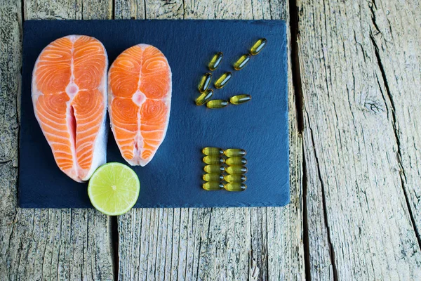 Two Salmon Steaks Lie Black Board Piece Lime Alongside Vitamins — Stock Photo, Image