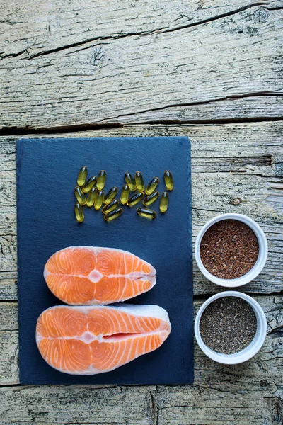 Two Salmon Steaks Lie Black Board Alongside Vitamins Seeds Chia — Stock Photo, Image