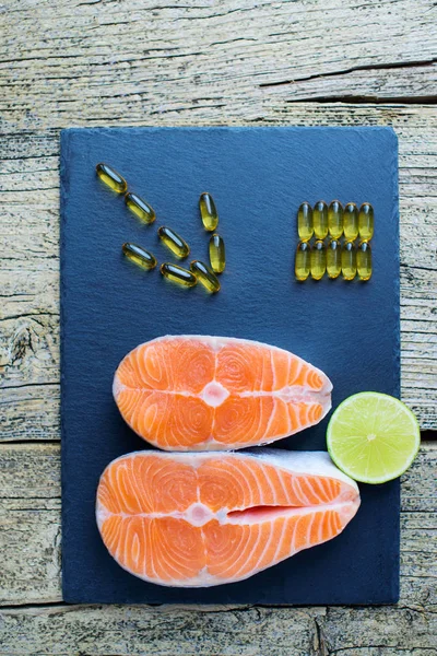 Two Salmon Steaks Lie Black Board Piece Lime Alongside Vitamins — Stock Photo, Image