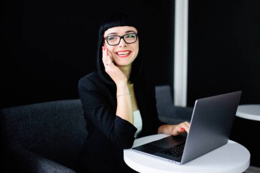 Güzel esmer oturma masada ve kafe ve telefonda konuşurken laptop kullanma.