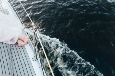 Bir yatta yalan ve havzanın arka plan üzerinde oturan bir kadının bacakları.