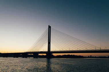 Şehrin iki parçaya böler günbatımı, arka planda büyük bir köprü.