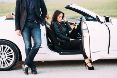 Kadın ve erkek tipik bir çift beyaz bir araba yanında şehir dışında vakit geçirmek.