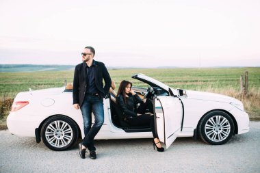 Kadın ve erkek tipik bir çift beyaz bir araba yanında şehir dışında vakit geçirmek.