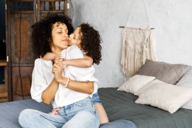 Anne ve küçük sevimli kıvırcık kız birlikte, sarılma ve öpüşme birbirlerine vakit
