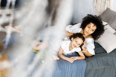 Ellerinde Lale ile anne ve oturan küçük sevimli kıvırcık kız yatak