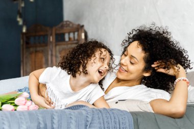 Ellerinde Lale ile anne ve oturan küçük sevimli kıvırcık kız yatak